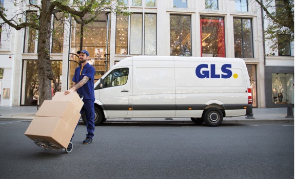 GLS delivery driver handling parcels in front of a GLS van in a city center, representing GLS France’s nationwide delivery network.