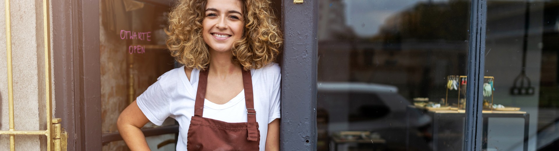 Woman shop owner smiling in front of her shop